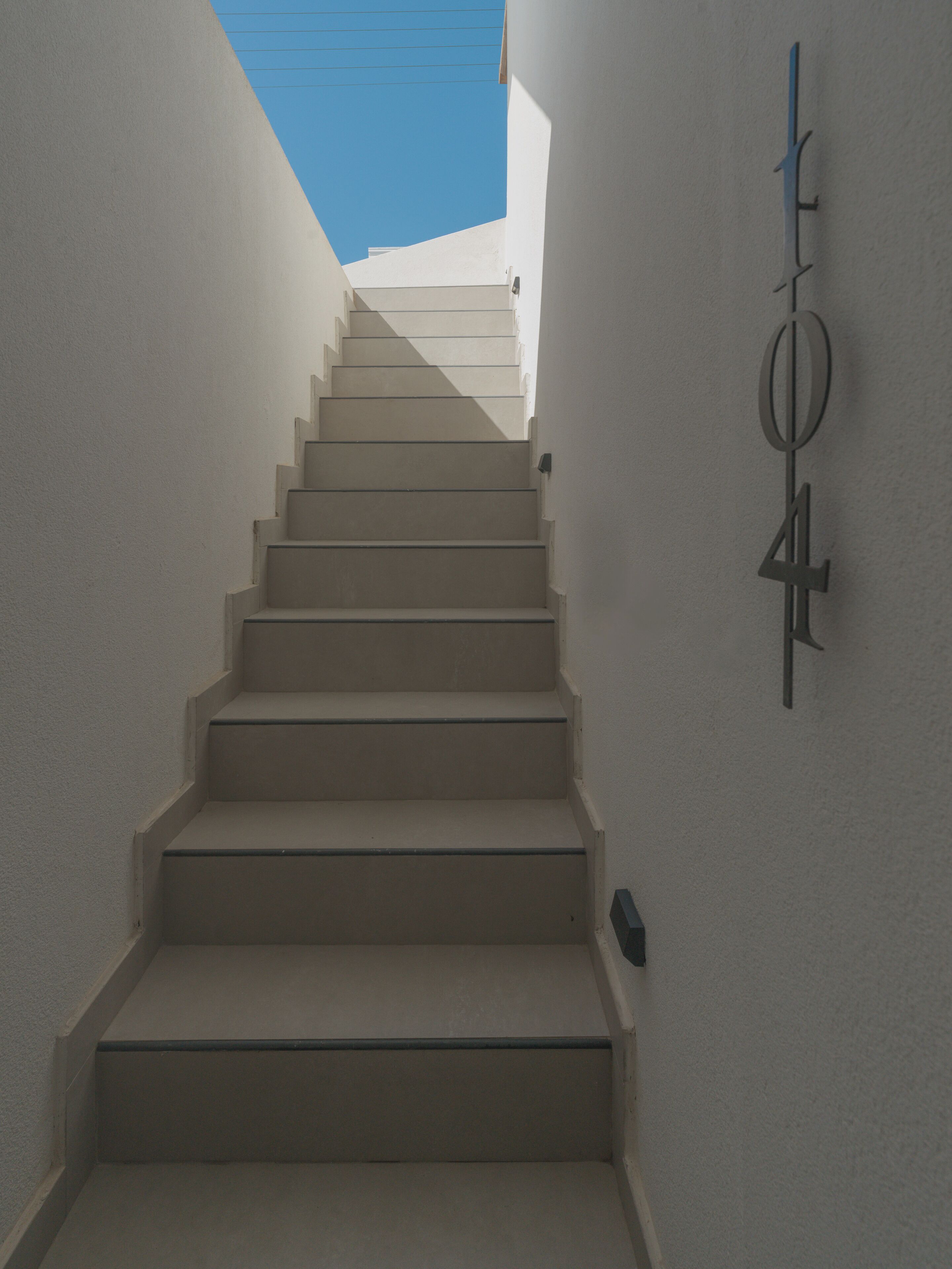 A staircase leading upwards in a building with a white exterior wall and a door marked with the number 4.