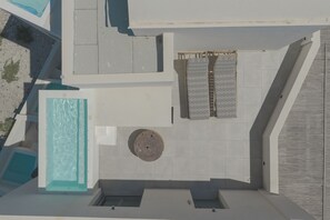 A rooftop terrace with a pool, seating area, and patterned curtains. - Anemos Imerovigli Suites (Santorini)