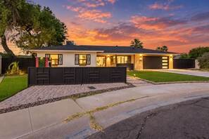 Ein modernes, zweigeschossiges Haus mit Garage, gepflegtem Rasen und Auffahrt zum Eingang.