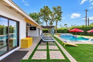Ein moderner Poolbereich im Freien mit Liegestühlen, einer gelben Sitzecke und freiem Blick auf den Pool.