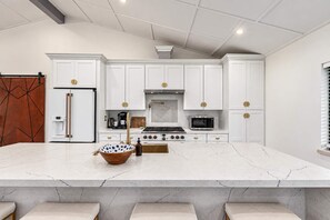 A modern kitchen with white cabinetry, a marble countertop, and a central island with seating.
