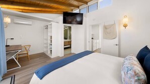 Un dormitorio con cama, escritorio, silla, televisor y armario.