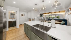 Una cocina moderna con una isla grande, electrodomésticos de acero inoxidable e iluminación colgante.