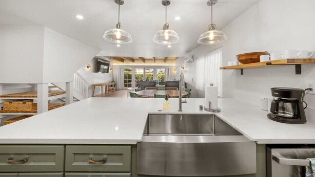 Una cocina moderna con una isla grande, pileta de acero inoxidable e iluminación colgante.