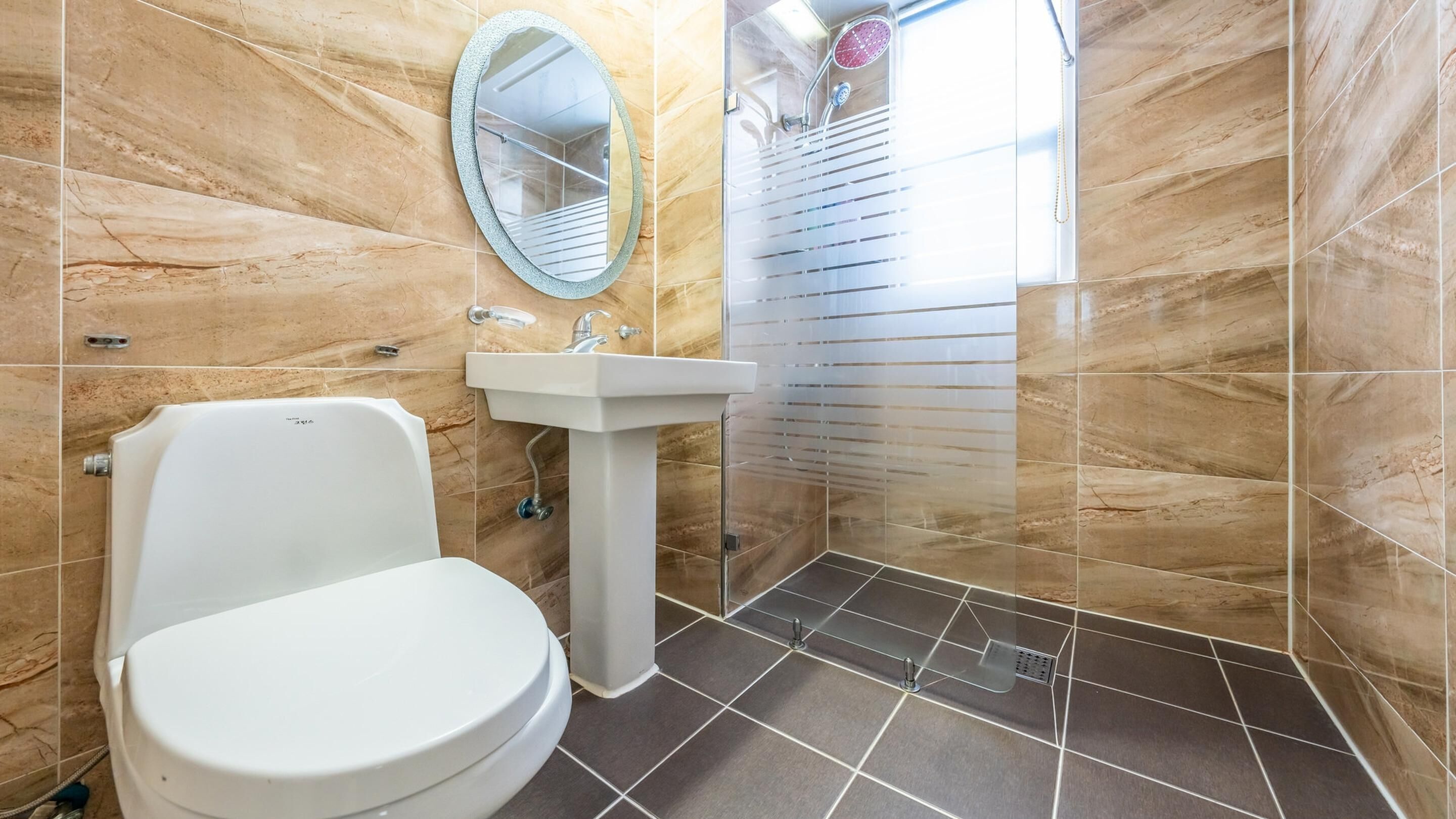 Une salle de bain avec des toilettes, un lavabo et une douche.