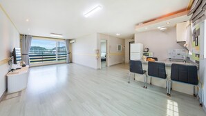 Ein geräumiges Zimmer mit Balkon, einer Küchenzeile und einem Essbereich mit Stühlen.