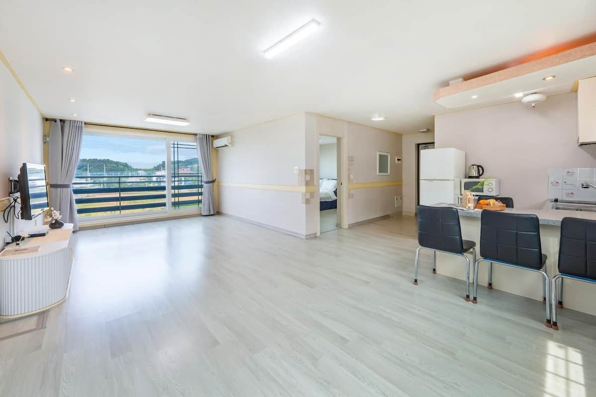 A spacious room with a balcony, a kitchenette, and a dining area with chairs.