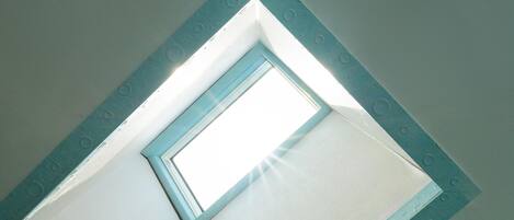 A skylight in a room with a white ceiling and a blue frame.