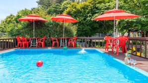 Ein Pool mit roten Sonnenschirmen, roten Plastikstühlen und einer Holzterrasse.