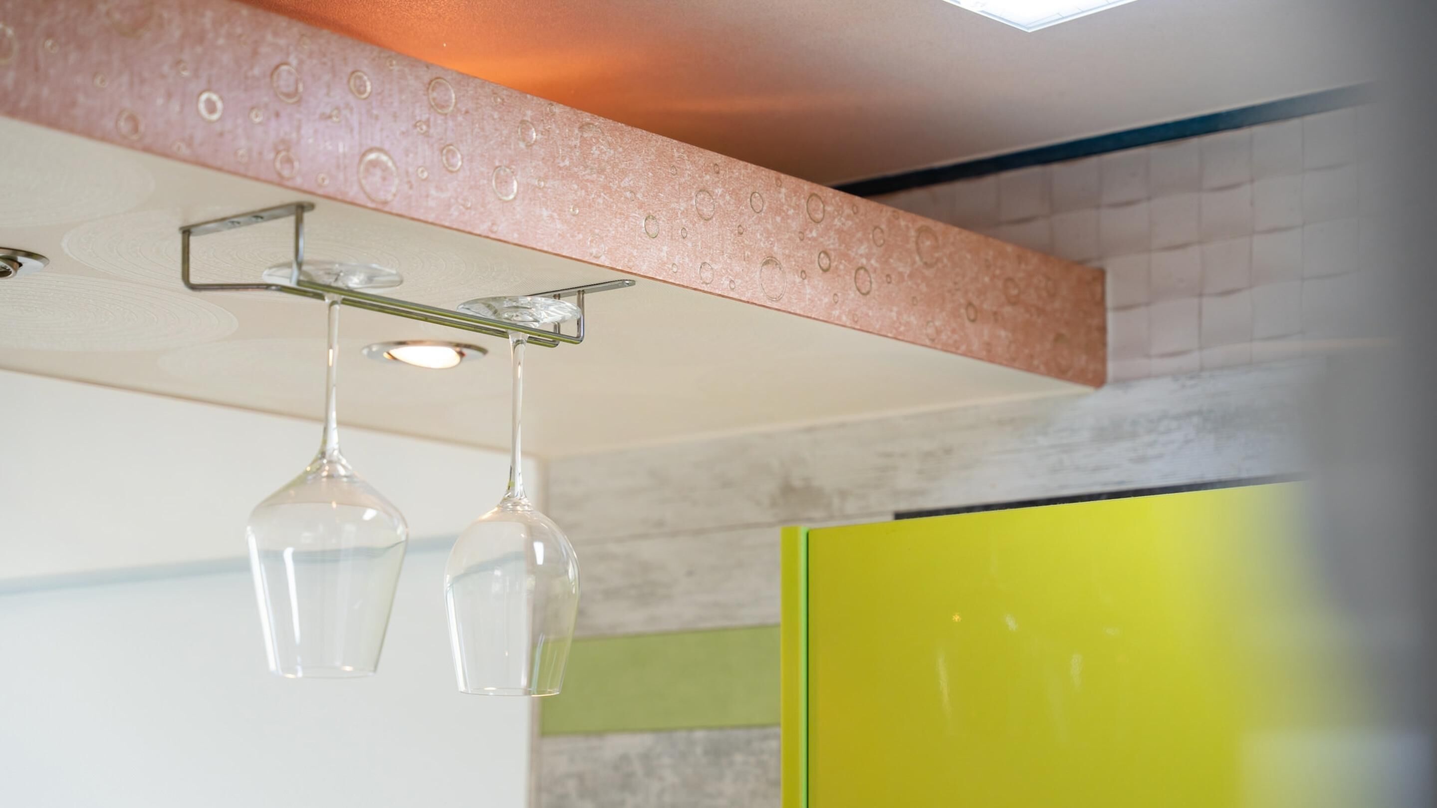 A kitchen with a hanging light fixture and a yellow cabinet.