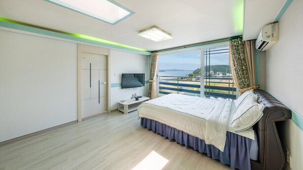 Ein Schlafzimmer mit Bett, Fernseher, Nachttisch, Kleiderschrank und einem Fenster mit Aussicht.
