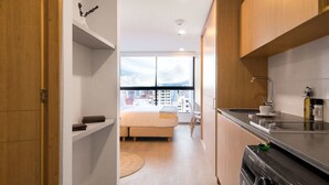 A modern kitchen with a built-in oven, a sink, and a window overlooking a cityscape. - w* | Perfect Loft in Santa Barbara (Bogotá)