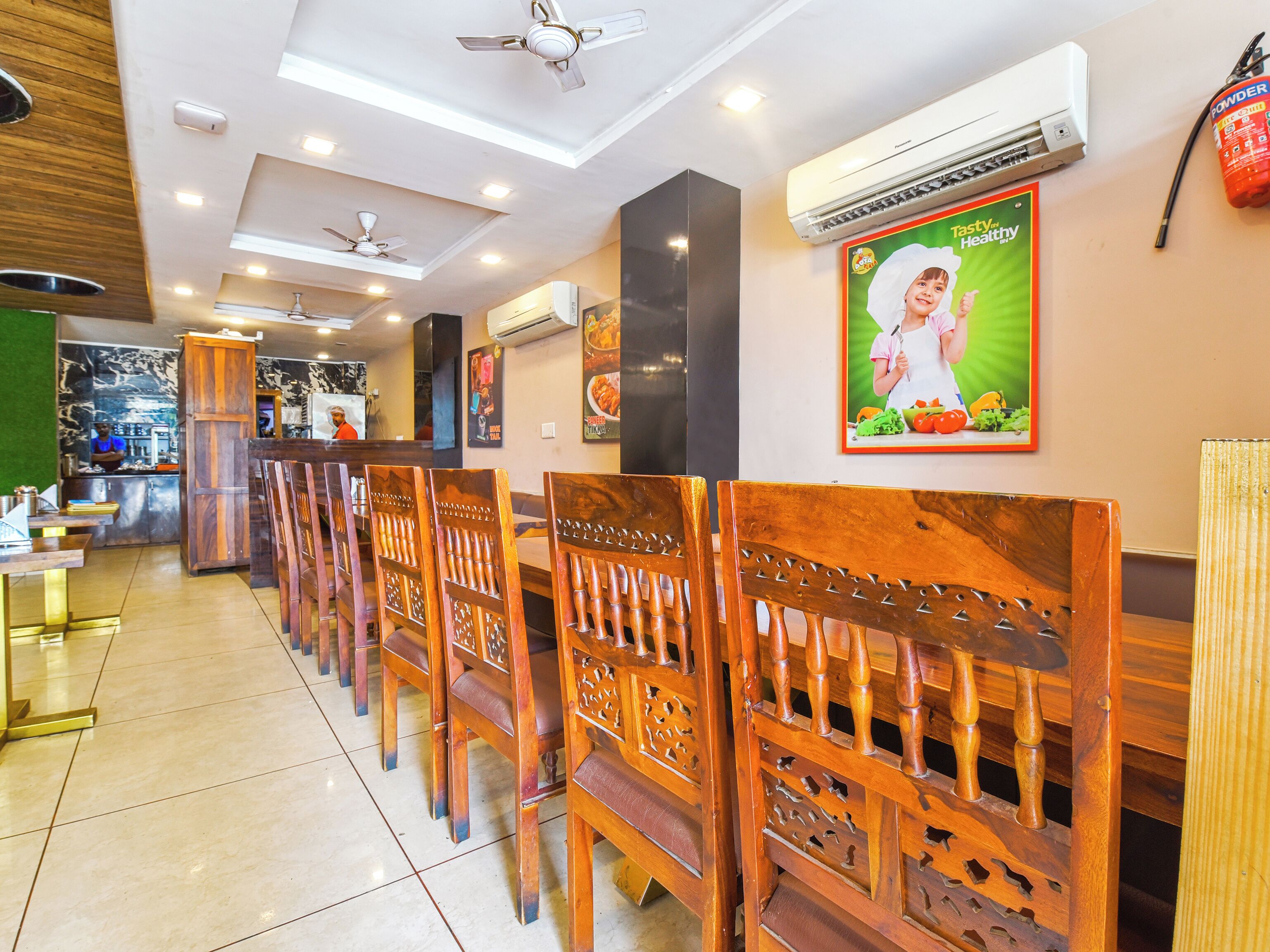 A restaurant with wooden chairs, ceiling fans, and an air conditioning unit.