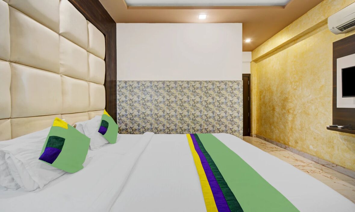 A hotel room with a large bed, a television mounted on the wall, and a patterned wallpaper.