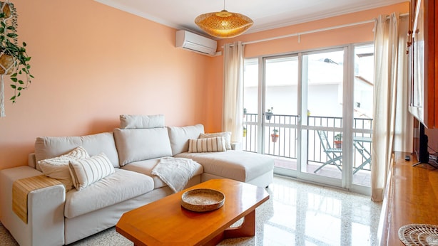 A living room with a sofa, a wooden coffee table, and a large window with a view of a balcony. - Urban Comfort by Casasol (Nerja)