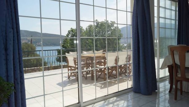 A room with a large sliding glass door leading to an outdoor patio with a table and chairs. - Villa Axia-Art 5pm from the sea (Evia)