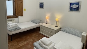 A bedroom with two single beds, a wooden wardrobe, a small bedside table with lamps, and a radiator. - Scarlatti in Florence (Florence)