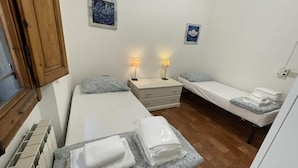 A small, clean room with two single beds, a nightstand, and a window with wooden shutters. - Scarlatti in Florence (Florence)
