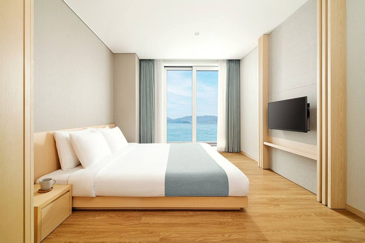 Et moderne hotelværelse med en stor seng, et fjernsyn og havudsigt.
