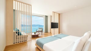 Een moderne hotelkamer met een groot bed, een zithoek met uitzicht op zee en een televisie.