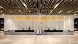 Een modern receptiegebied met een strak, minimalistisch design, bestaande uit een centraal gelegen balie met personeel, een decoratief plafond en een gepolijste vloer.