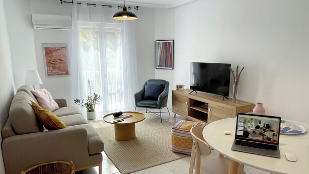 A modern living room with a sofa, armchair, coffee table, TV, and a laptop on a small table. - Apartamento La Peatonal (Hervás)