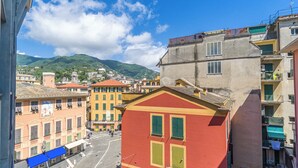 Una vista di strada con edifici colorati, un attraversamento pedonale e una montagna sullo sfondo.