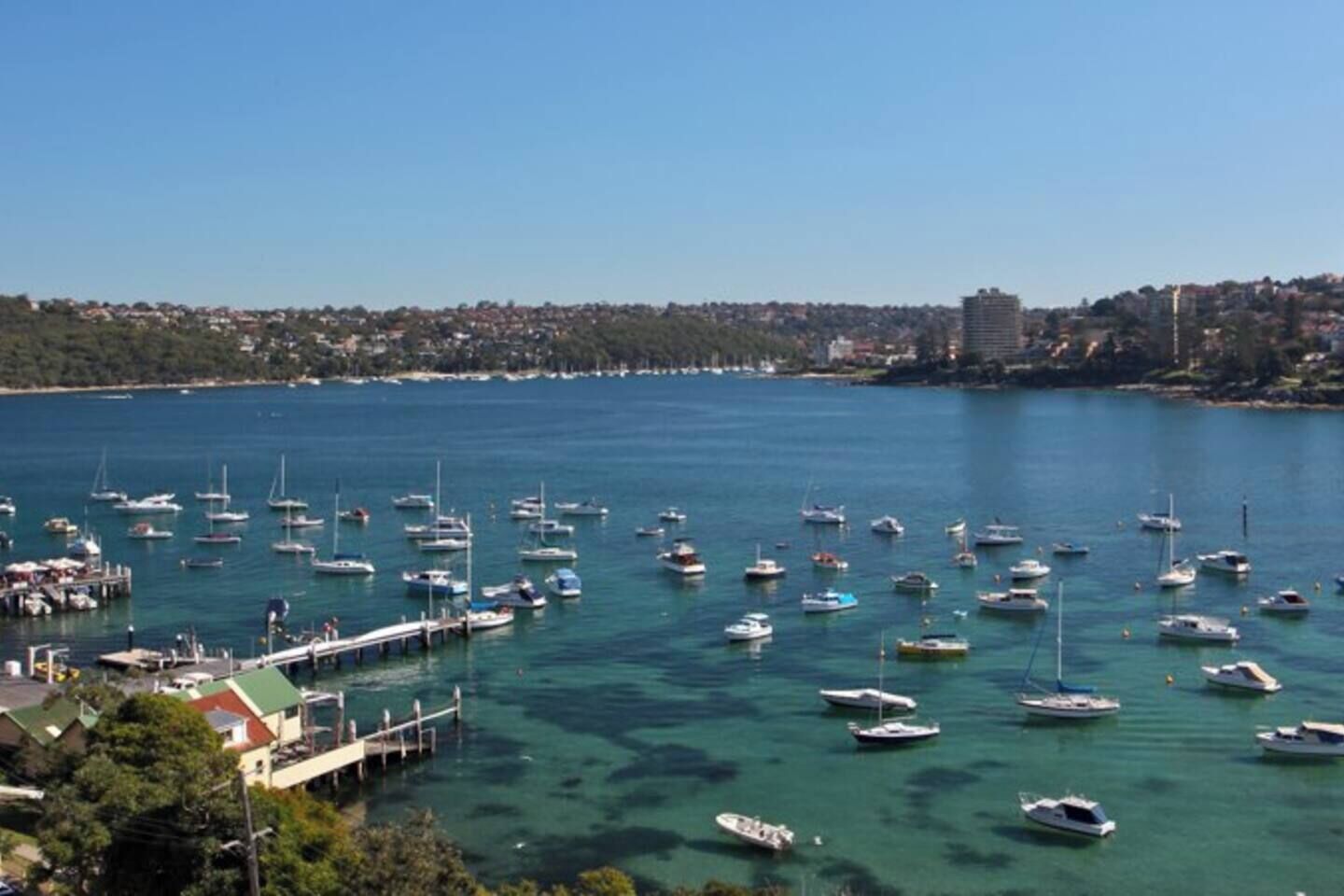A marina with numerous boats docked, surrounded by a coastal town.