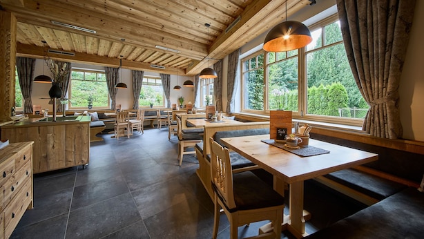 Un interior rústico de madera con varias zonas de estar, ventanas amplias y una mesa central con una carta.