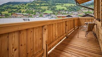 A wooden deck with a view of a village and mountains.