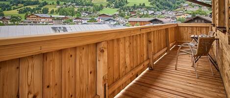 A wooden deck with a view of a village and mountains.