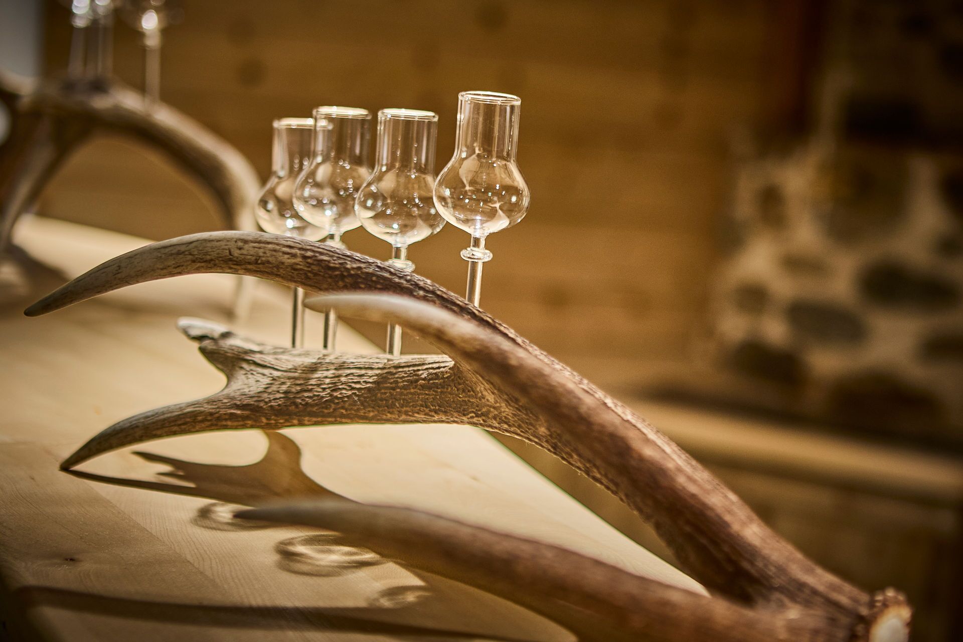 A table with a large antler and several wine glasses.