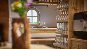 Un interior de madera con un amplio ventanal de arco, un mostrador de madera con vitrina y un refrigerador.