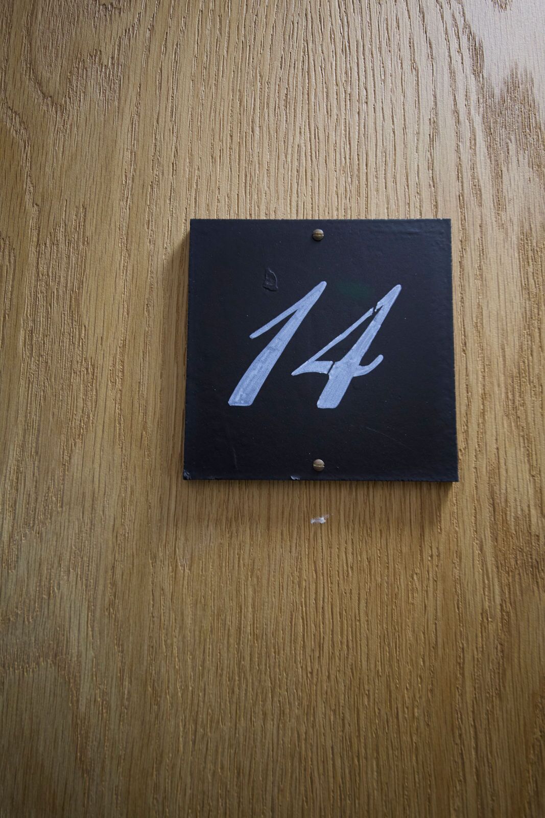 A black sign with the number 14 on a wooden surface.