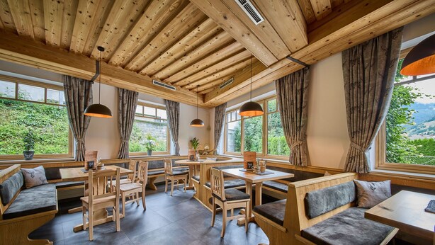 Un restaurante acogedor con muebles de madera, ventanas amplias y vistas al verdor.