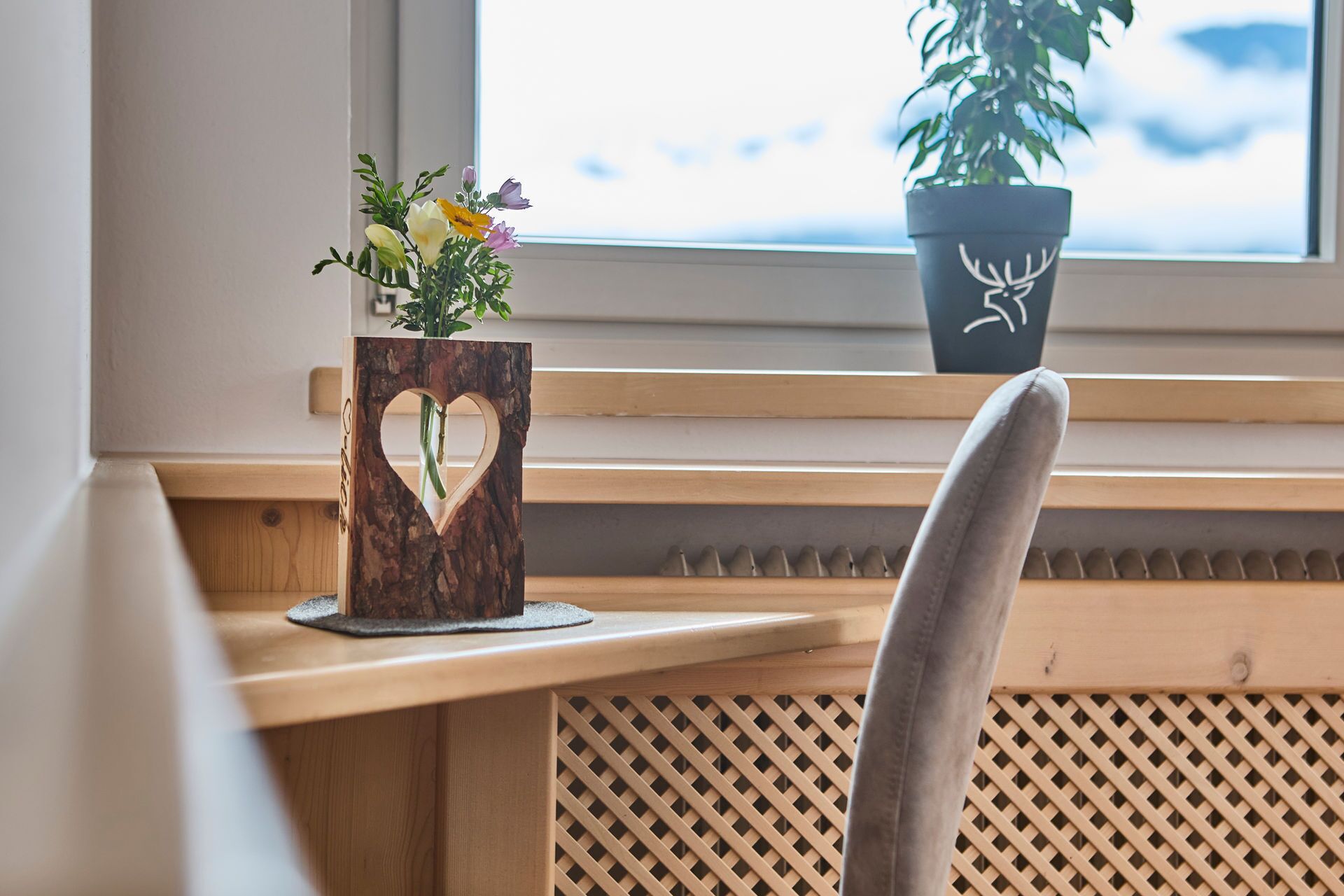 A wooden bench with a heart-shaped cutout holding a flower arrangement.