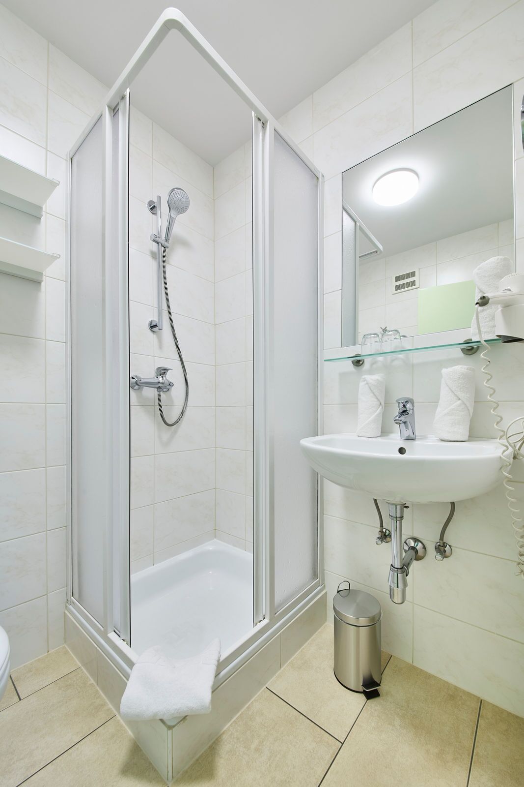 A modern bathroom with a glass-enclosed shower, a white sink, and a mirror above the sink.