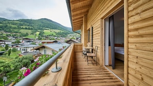 Un balcón de madera con mesa y sillas, con vistas a un pueblo y montañas.