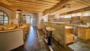 Un interior de madera con una zona de bar, asientos y una pared decorativa de piedra.