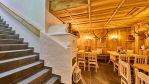 Un interior de madera con una escalera, una zona de comedor con muebles de madera y adornos de asta de ciervo.