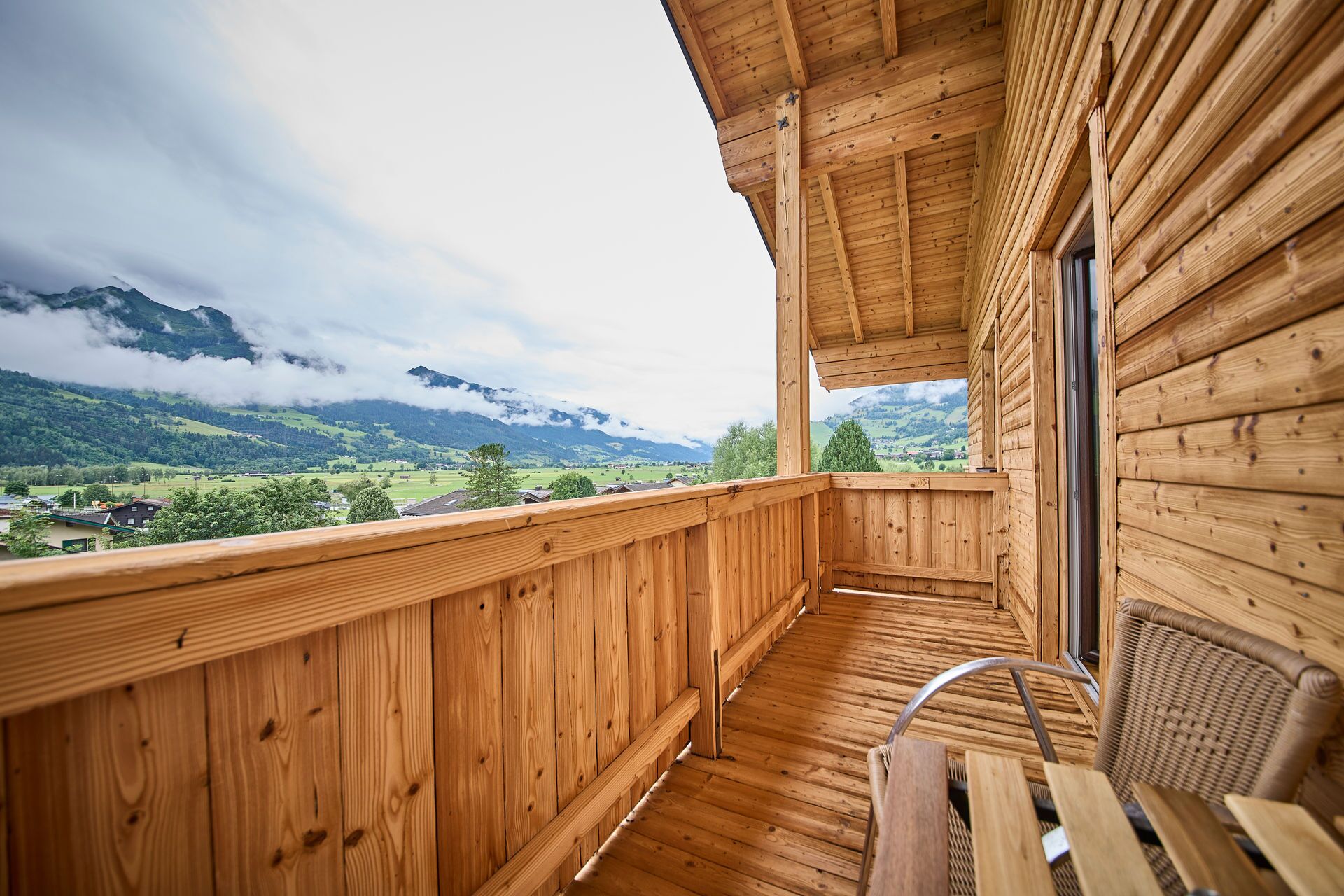 A wooden balcony with a view of a mountainous landscape.