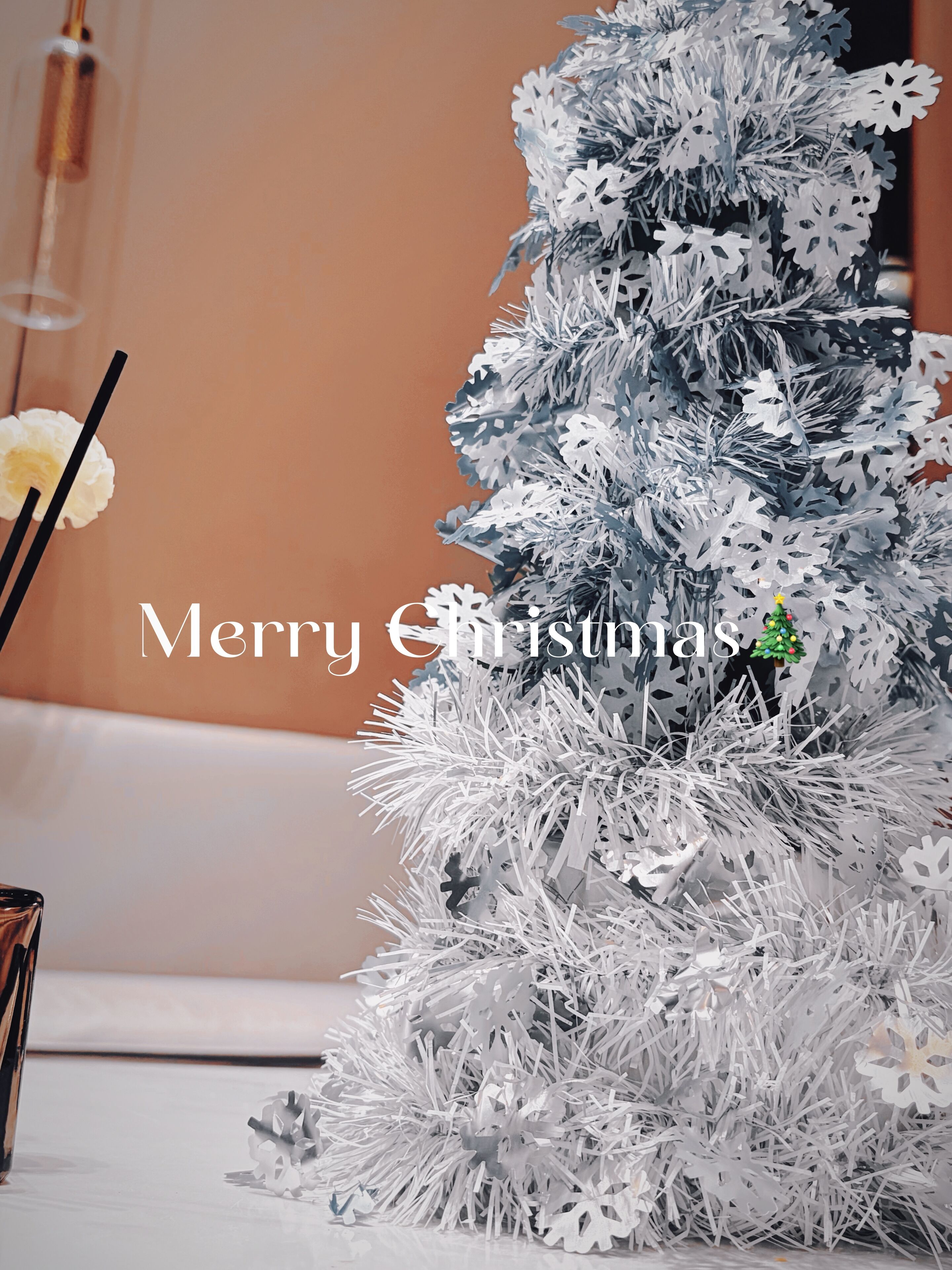 A Christmas tree with snowflake decorations and a small Christmas tree ornament.