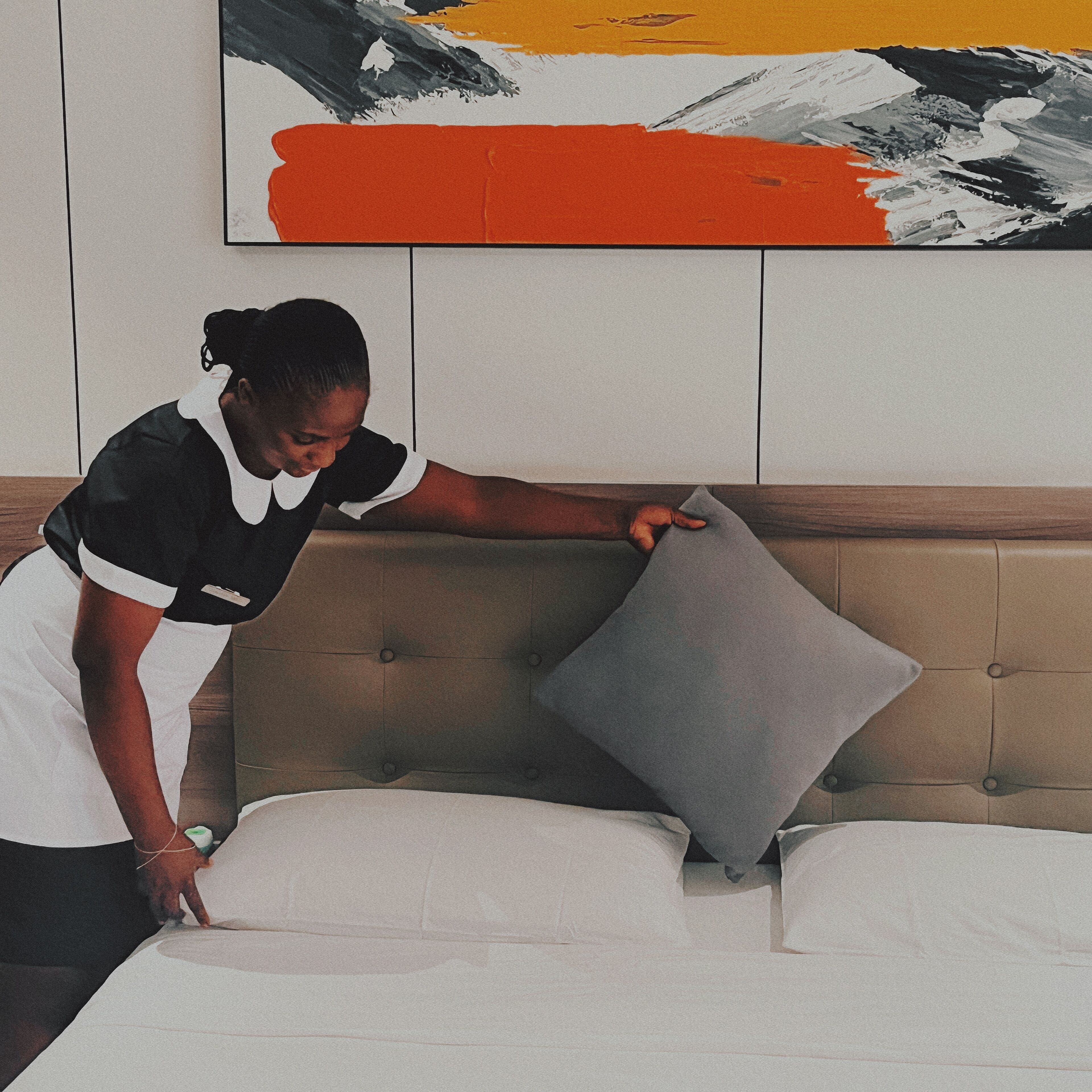A person adjusting a pillow on a bed in a hotel room.