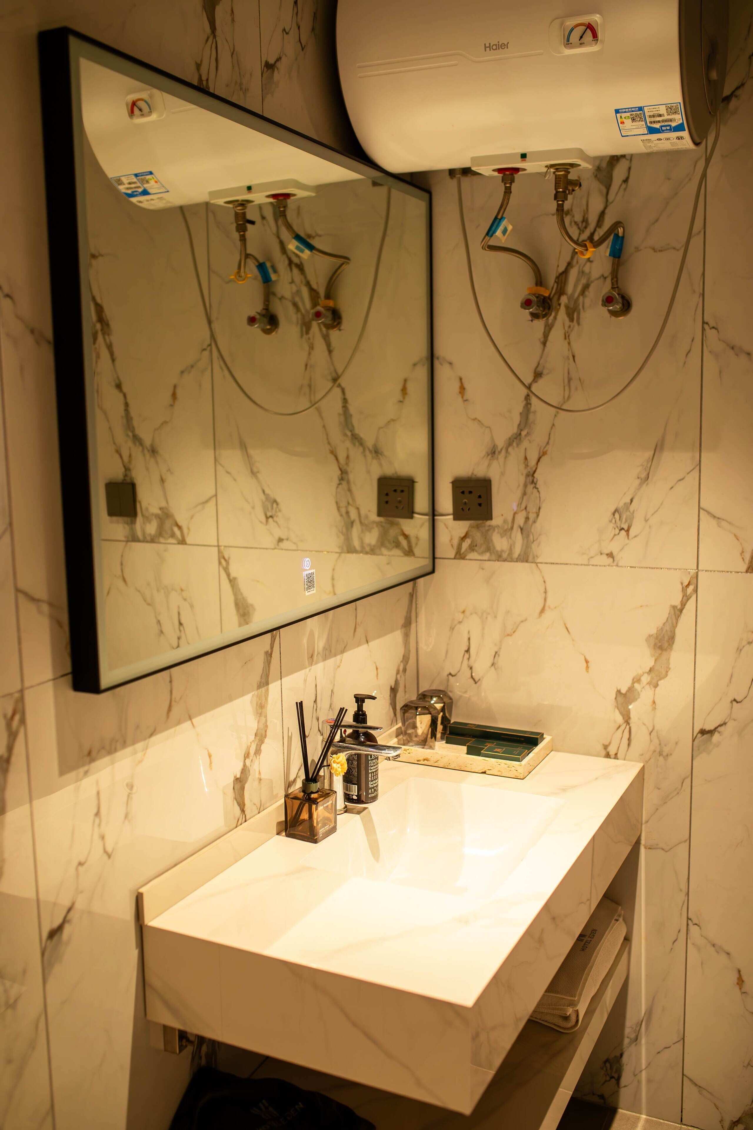 Une salle de bain avec un lavabo en marbre blanc, un miroir et une douchette à main.