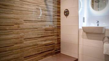 Ein modernes Badezimmer mit einer Holzvertäfelung, einer Duschkabine aus Glas und einem Waschbecken mit Spiegel.
