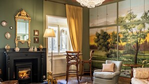 A cozy living room with a fireplace, comfortable seating, and a large window with a scenic view. - Palazzo Radici (Bergamo)