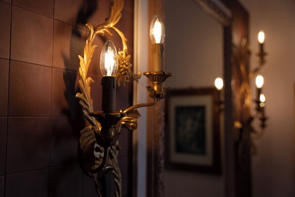A wall-mounted candle-style light fixture with a decorative design. - Palazzo Radici (Bergamo)