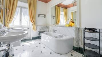 A bathroom with a large bathtub, two sinks, and a vanity with a mirror.