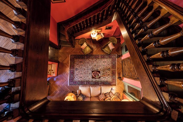 A grand staircase with wooden balusters, a patterned rug, and a sofa with cushions. - Palazzo Radici (Bergamo)