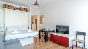 Ein modernes Hotelzimmer mit einem Bett, einem Fernseher, einem Esstisch und einem roten Schrank.